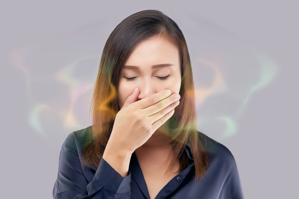 Persoană care își verifică respirația, halena fiind un semn de igienă dentară deficitară